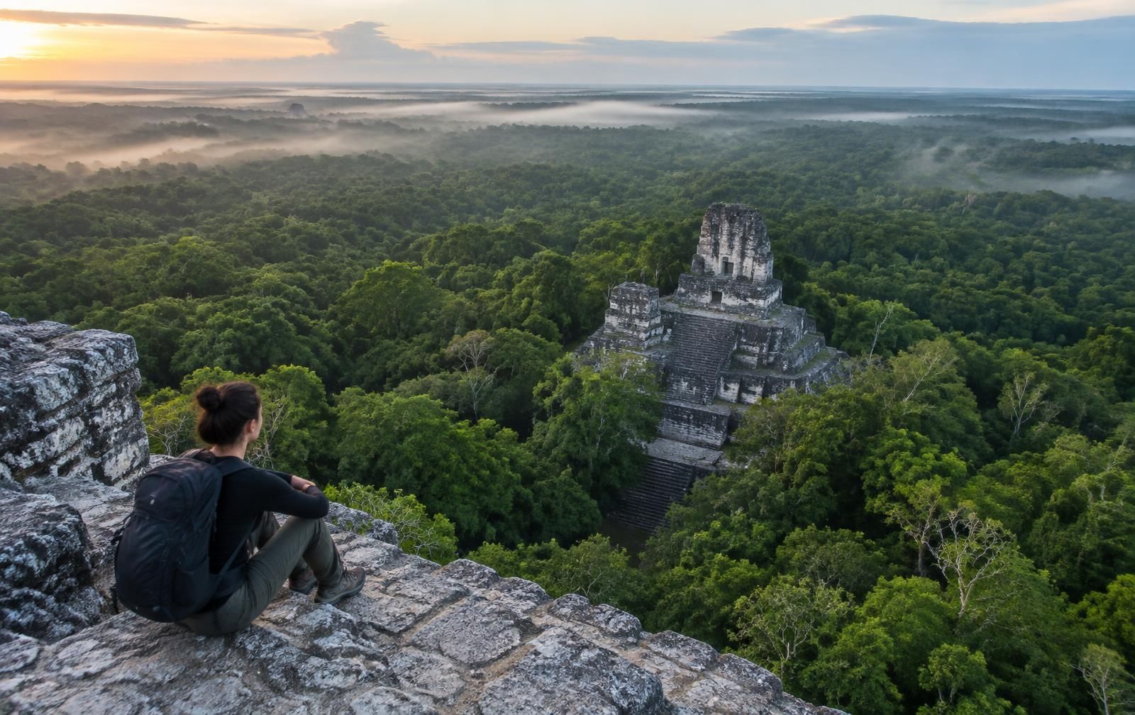 Una viajera sobre una pirámide maya frente a la selva de Calakmul